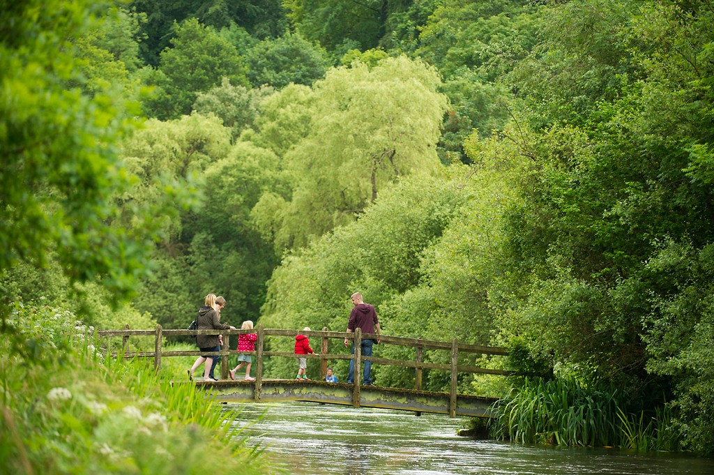 A family cross a bridge over the River Itchen near Ovington Hampshire, UK